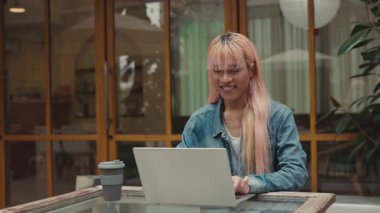 Pembe Peruklu Adam dışarıda dizüstü bilgisayarda çalışıyor. Bir Çevrimiçi Şirketin Eşcinsel Çalışanı Sokağın Kafesi 'nde otururken Bilgisayar kullanarak Sorulara Cevap Veriyor. LGBT ve Teknoloji Konsepti