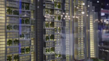 Modern çok katlı evin minyatür maketi. Balkonları süsleyen dekoratif ağaçları var. Emlak fuarında apartman binasına panoramik manzaralar sunuluyor