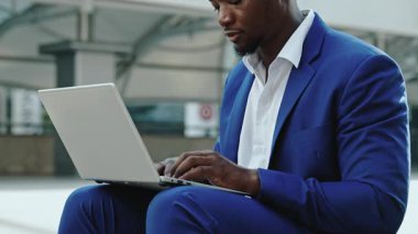 Ciddi bir Afrikalı Amerikalı girişimcinin portresi, şehir merkezindeki dizüstü bilgisayardaki ortağına e-posta yazıyor. Sakallı iş adamı şehir merkezinde internet üzerinden sunum yapıyor.