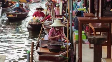 Damnoen Saduak, 5 Haziran 2025: Taylandlı kadın ünlü yüzen markette teknesinden satay şiş ızgara yapıyor..