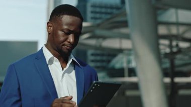 Afro-Amerikalı bir adamın portresi, şehir merkezindeki tablete bakmakla ilgili endişelerini dile getiriyor. Düşünceli genç tüccar iş merkezinin yakınındaki online tekliften şüphe duydu. E ticaret teknolojisi