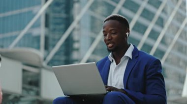 Dost canlısı Afro-Amerikan iş adamlarının portresi şehir planındaki laptop kamerasına merhaba diyor. Ofis çalışanı şirket binasına karşı otururken online çağrıya cevap veriyor