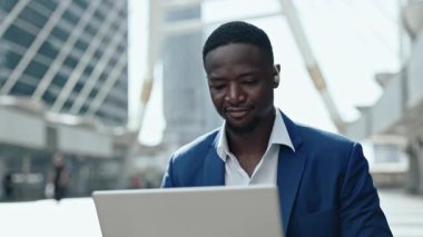 Modern şehirdeki işitme engelli Afro-Amerikan çalışanlarının portresi dizüstü bilgisayarda çalışıyor. Engelli işadamı, şehir merkezinde ticari veriler.