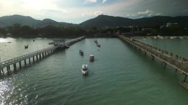 Rıhtım ve köprü, sürüş arabalarıyla körfezi geçer ve yelkenliler güneş doğduğunda dağlara karşı masmavi sularda yelken açarlar. Çeşitli yatlar Tayland 'da turistler için büyüleyici bir deniz yolculuğu sunuyor