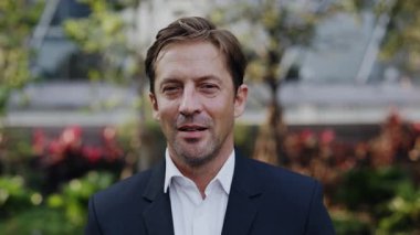 Resmi takım elbiseli dost canlısı iş adamının portresi şehir parkında duran kameraya bakıyor. Olgun girişimci, ofis binası dışında kendine güven yayar. Şirket CEO 'su