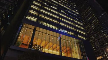 Large illuminated conference hall of business center in evening business downtown low angle shot. Financial organization skyscraper with glass facade in Asian urban landscape