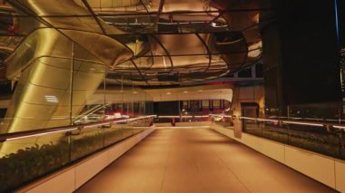 HONG KONG, CHINA - MAY 19 2025: Empty glass corridor and terrace lit by dim light in Henderson building at night. Futuristic public place to observe city beauty in evening. Architectural concept