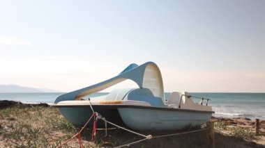 Blue boat on a sandy beach. The sea is calm. 