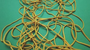 Yellow office rubber bands on a green surface. Close-up shot. High quality 4k footage