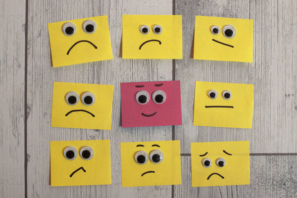 Positive attitude with office notes with multiple faces and one that stands out with a smile
