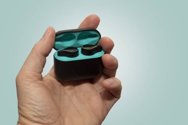 Yeşil arkaplanda siyah bluetooth kulaklıklar var.