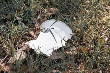 Plastik bir tabak, çayırdaki kirlilik kavramı.