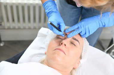 Mikroplu patinaj yakın çekim, eller kaşlara pigment ekliyor, kadın kafası.