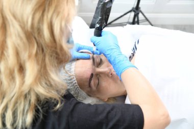 Mikroplu patinaj yakın çekim, eller kaşlara pigment ekliyor, kadın kafası.