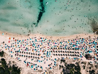 Renkli şemsiyeli kumlu sahil manzarası, tanınmayan insanlar, yazın güneşli bir günde şeffaf mavi suyu olan deniz kıyıları. Mallorca 'da seyahat, Balear adaları, İspanya. Üst Manzara. Tropik