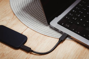 Tahta masadaki dizüstü bilgisayara bağlı harici yedek disk sürücüsü