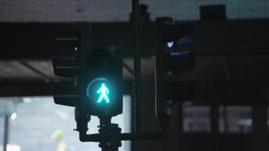 Pedestrian traffic light changes red while several buses pass in front of it