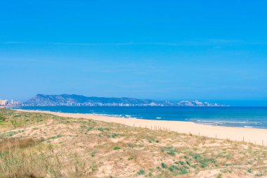 Uzakta Cullera şehri manzaralı bir sahil.