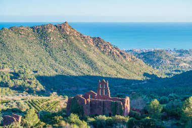 İspanya 'nın Castellon Eyaleti' ndeki Desert de les Palmes Doğal Parkı manzaralı bir manastır harabeleri ve arka planda mavi Akdeniz