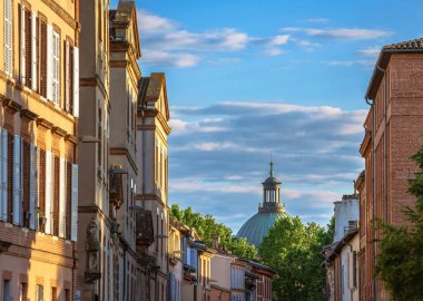 Toulouse, Fransa. La Grave Hastanesi 'nin ikonik kubbesine doğru dar bir yerleşim yeri var. Ağaçlar ve arka planda yumuşak bulutlar olan altın saat güneş ışığıyla aydınlatılıyor..