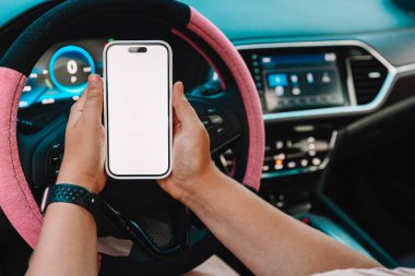Arabadaki bir kadının ellerinde izole bir ekran olan bir telefon..