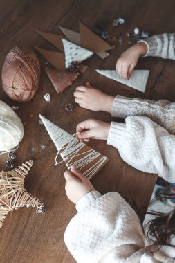 Çocuk iplikten Noel süsü yapıyor.