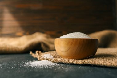 Çuval bezi üzerinde tahta bir kasede şeker.