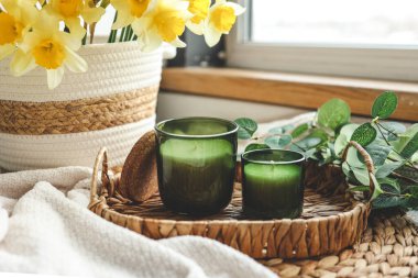 İki mum ve içinde nergis olan bir sepet..