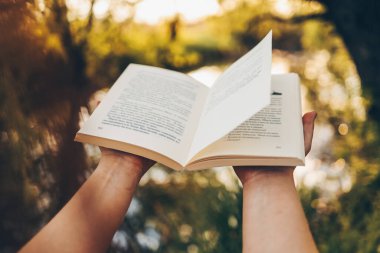 Günbatımı arka planında açık bir kitap. Okuma, çalışma, okul. Açık havada bir kitap oku..