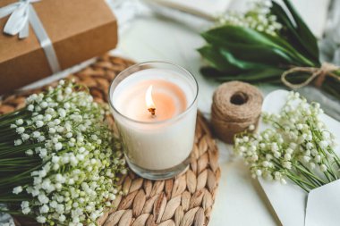 Beyaz, yanan bir mum ve bir buket vadi zambağı, doğal bir bahar fotoğrafı..