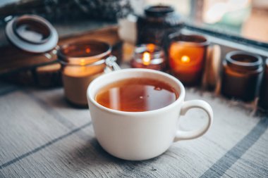 Bir fincan bitki çayı, yanan mumlar, estetik olarak sıcak bir fotoğraf..