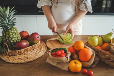 Hamile kadın mutfağında salata yapıyor..