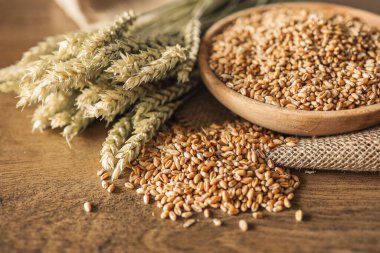 Buğday ve buğday taneleri kahverengi ahşap zemin üzerinde kase