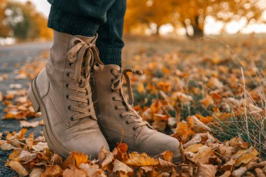 Bir adam sonbahar yolu boyunca yürüyor, botları yakın çekimde..