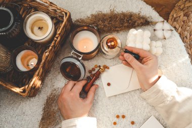 Kız tebrik kartı yapıyor ve zarfı balmumu mühür ile mühürlüyor.