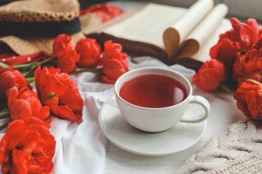 Güzel bahar kompozisyonu, günaydın konsepti. Bir fincan çay, şakayıklar, açık eski kitaplar..