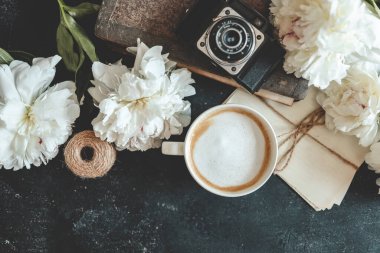 Summer composition top view. Cup of coffee, peonies and retro camera, wallpaper, space for your text.