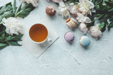 Bir fincan çay, badem kurabiyesi ve şakayık, düz bir manzara. Günaydın konsept.