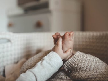 Beşikteki yeni doğmuş bebek, kollar ve bacaklar yakın çekim, annelik estetiği.