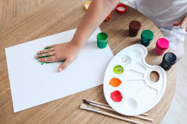 Çocuk çizim yüksek lisansı, çocuk boyayla el izi yapıyor..