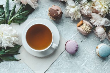 Bir fincan çay, badem kurabiyesi ve şakayık, düz bir manzara. Günaydın konsept.