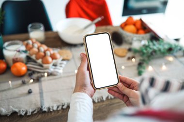 Noel yemeğinin arka planında boş ekranlı bir telefon. Mesaj için yer. Ana sınıf davetiyesi. Mutlu Noeller.