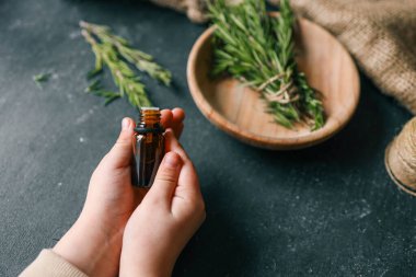 Esans taze biberiye dallar üzerinde karanlık bir arka plan ile bir şişe.