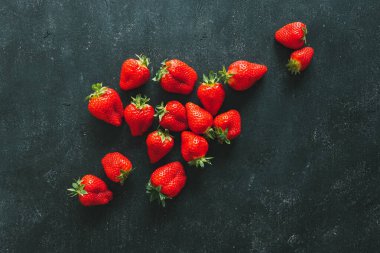 Olgun çilek yığını siyah ahşap arka planda fotokopi alanı ile. Üst görünüm.