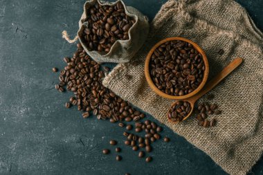 Coffee beans in a wooden plate on a black background.