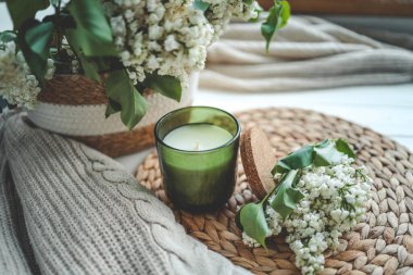 Yeşil bir kavanozda mum, açık bir kitap ve bir buket beyaz leylak, bahar içleri..