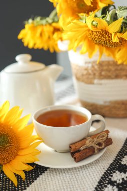 A cup of tea and a teapot with a candle on a table with sunflowers, tea time, aesthetics