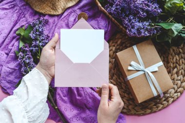 Bir kadının elleri zarf içinde bir mektup tutuyor. Anneler Günü ya da Sevgililer Günü konsepti. Metnin için yer.