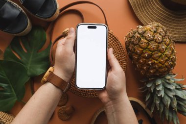 Yaz aksesuarlarının arka planında izole bir ekran olan telefon ellerinizde. Reklamınız için bir yer..