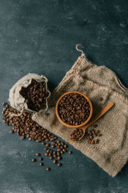 Coffee beans in a wooden plate on a black background.